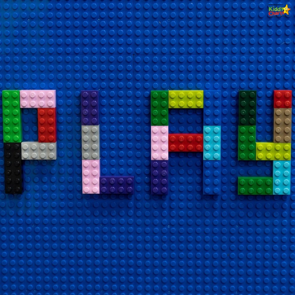Colorful LEGO bricks spelling "PLAY" on a blue baseplate, with bright hues of red, yellow, green, and purple for a playful design.