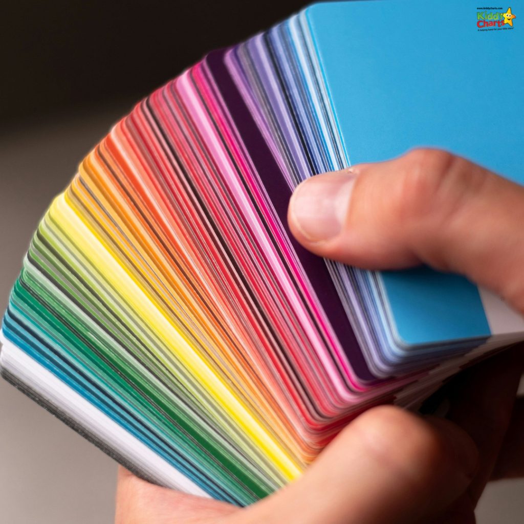 A person holds a fan of colorful cards, displaying a vibrant spectrum from blue to green, yellow, orange, pink, and purple.