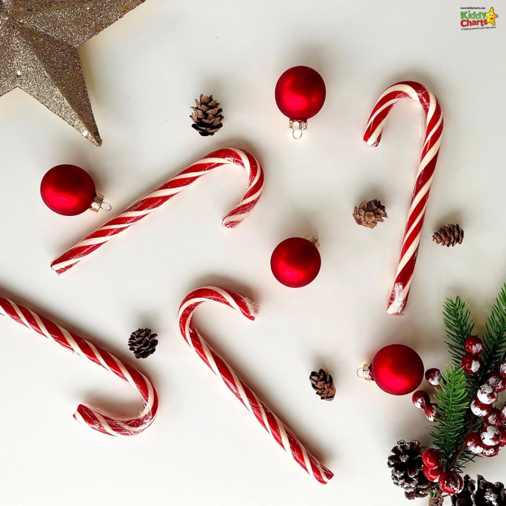 Festive Christmas scene with red candy canes, red baubles, pinecones, and greenery on a white background, creating a holiday atmosphere.