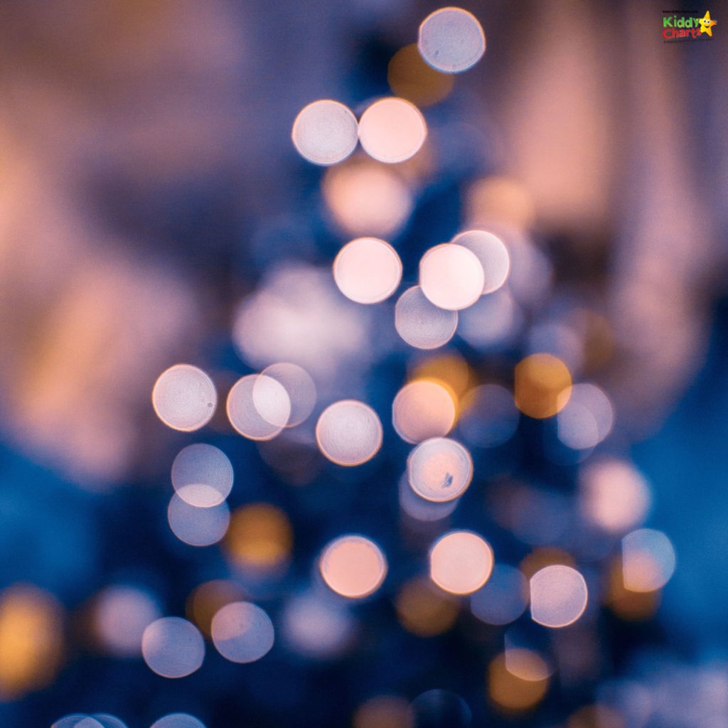Blurred bokeh lights create a festive, dreamy atmosphere, featuring warm colors against a cool blue background, resembling a glowing, out-of-focus Christmas tree.