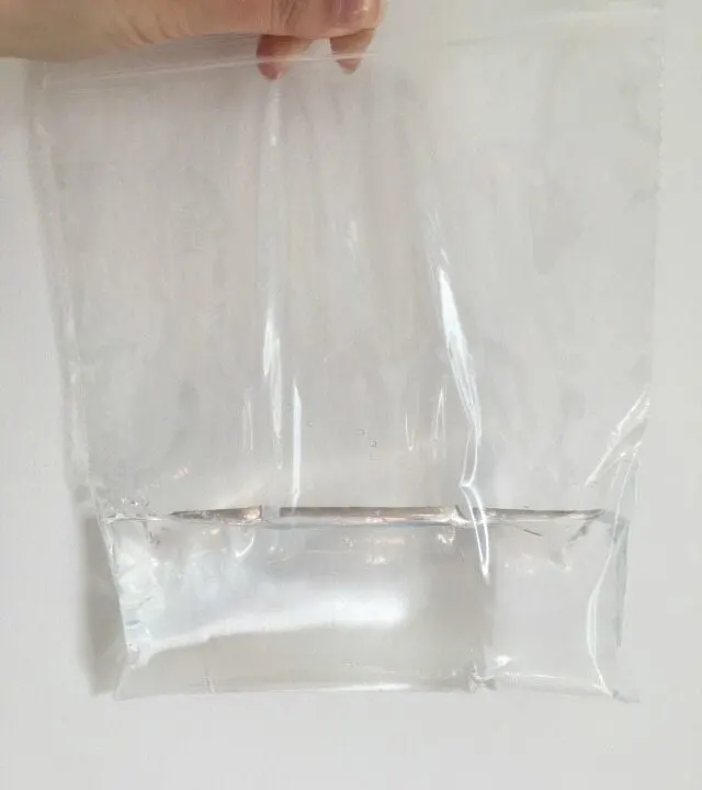 A person is packing materials in a transparent plastic material indoors.