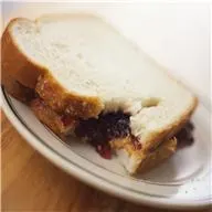 A plate of freshly-baked Texas Toast, sliced wheat gluten loaf, and whole wheat bread sits on a white table indoors, ready to be enjoyed as a breakfast, snack, or fast food dish.