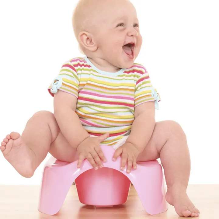 A newborn baby is smiling while wearing a toddler-sized outfit indoors.